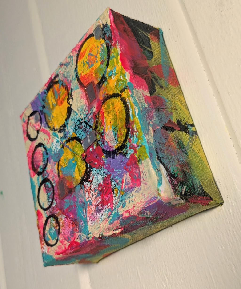 Abstract art piece with colorful circles on a white wall